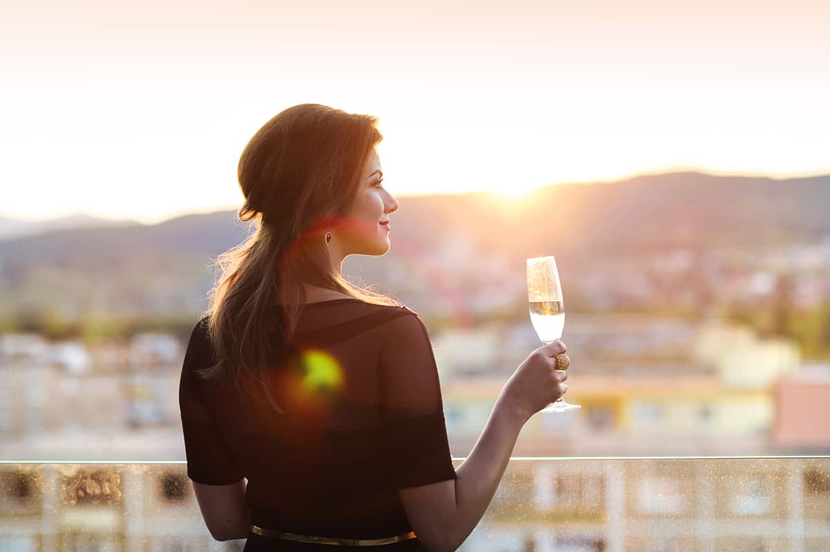 Young woman with a drink of Champagne on a terrace of a bar