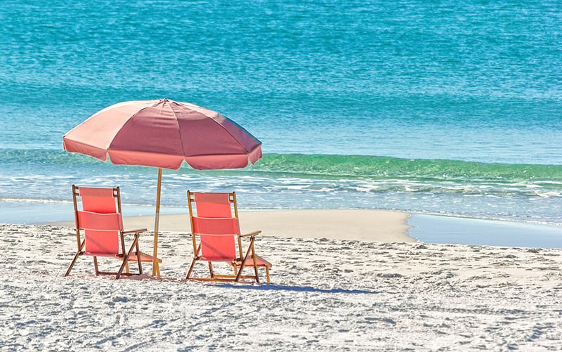 Pink umbrella and lounge chairs on the Miramar Beach in Destin, Florida