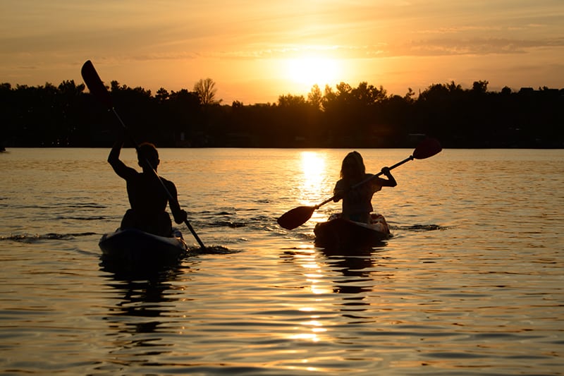 Couple Paddling Kayaks at sunset