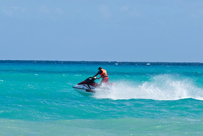 Man riding jet ski on green blue water - a popular activity and tour when visiting Crab Island