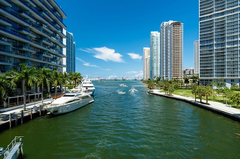 Downtown Miami along the Miami River inlet with Brickell Key in the background and yachts at the dock.