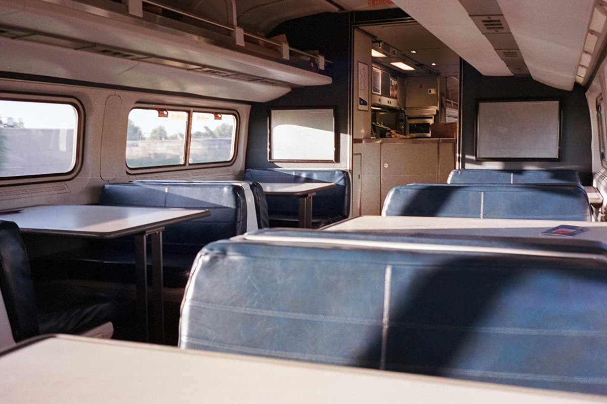 Club car with chair and tables in an Amtrak train - one of the many amenities that is offered onboard