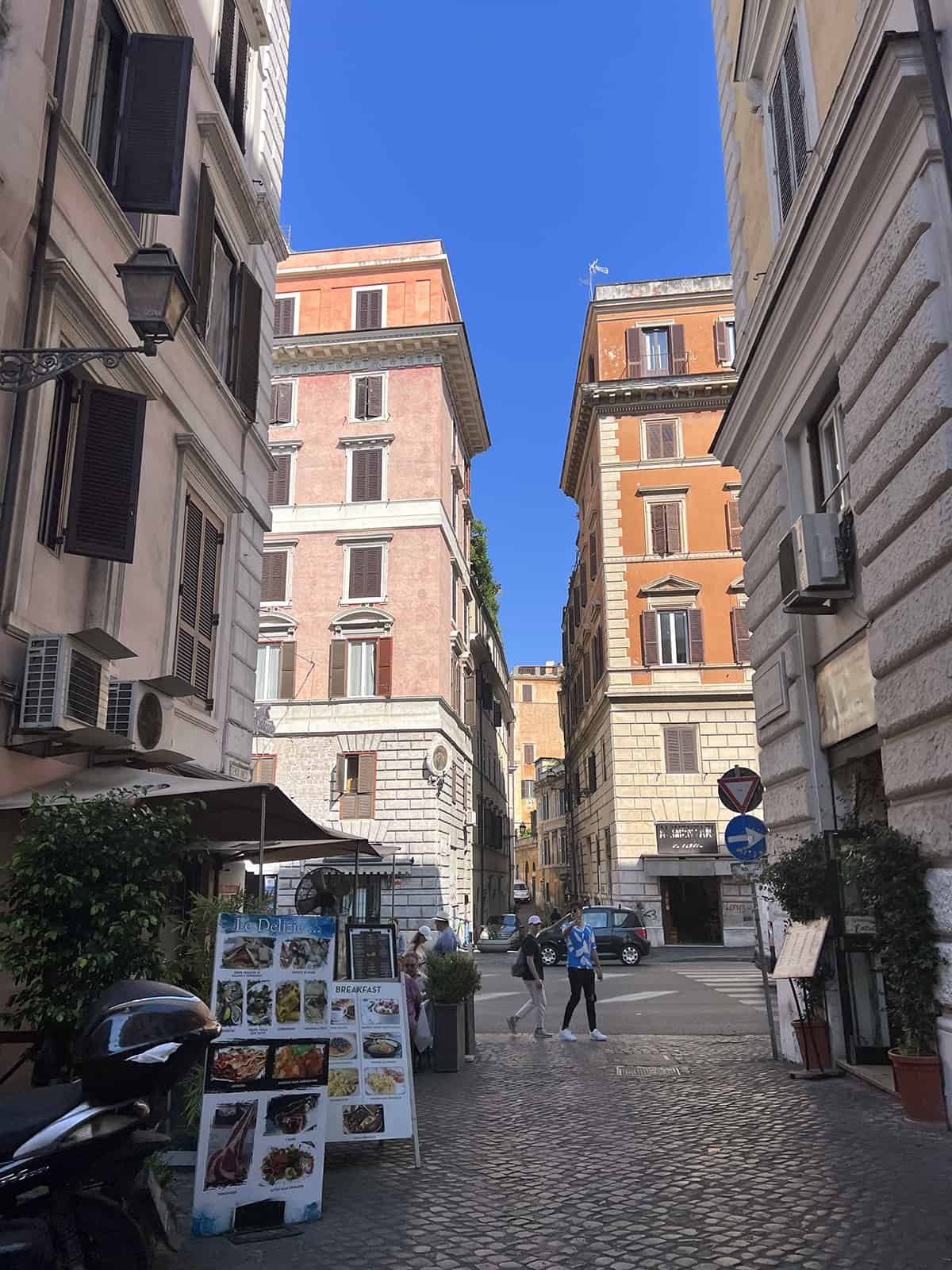 Narrow street with bright orange and pink colored buildings in Rome, Italy - a street accessible by a golf cart
